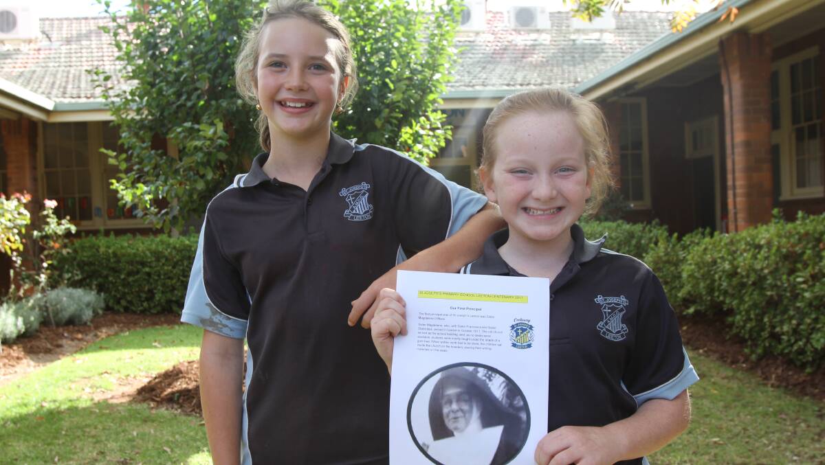 CELEBRATIONS: St Joseph's students Alexa Burgess, 9, and Lila Day, 9, pose with a picture of the school's first principal from 1917.