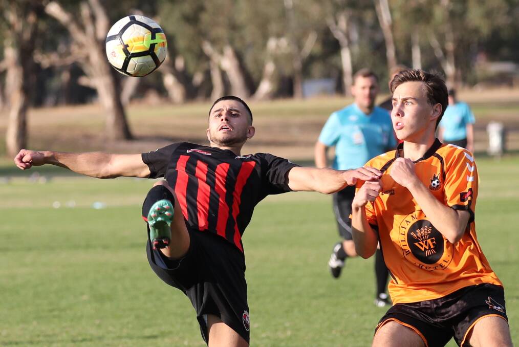 TRICK SHOT: Leeton United's Anthony Trifogli looks to get boot to ball in front of Wagga United's Dan Cain at Rawlings Park on Sunday. Pictures: Les Smith