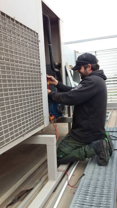 TECHNICIAN Dean Rae completes work on a commercial air-conditioning system in Leeton.