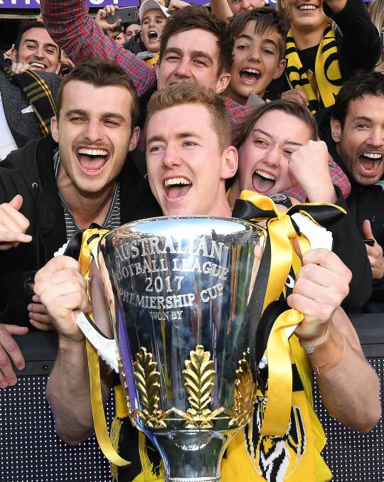 Leeton's Jacob Townsend - one of Richmond's so-called "unknown" heroes - holds the ultimate silverware with friends Mathew Grundy (left) and Liam Frazer (behind). Photo - AAP Image/Julian Smith