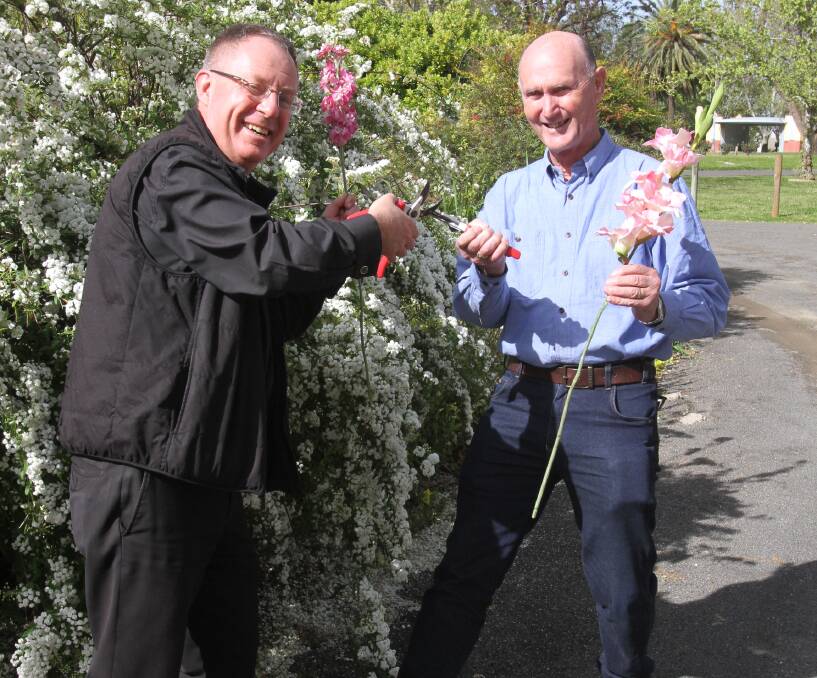 WIN: Father Robert Murphy from St Peter's and Alan Chesworth from St Andrew's tussle over who will be named the overall winner of the flower shows at both fetes. 