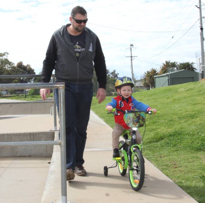 PRACTICE MAKES PERFECT: Andrew Valenta guides Jake Diggelmann, 2, down the path at Bike Week celebrations in Leeton. Photo: Ron Arel