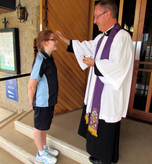 MEANINGFUL: Kate McAliece, 10, receives ashes from Father Robert Murphy. This week marks both Shrove Tuesday and Ash Wednesday. 