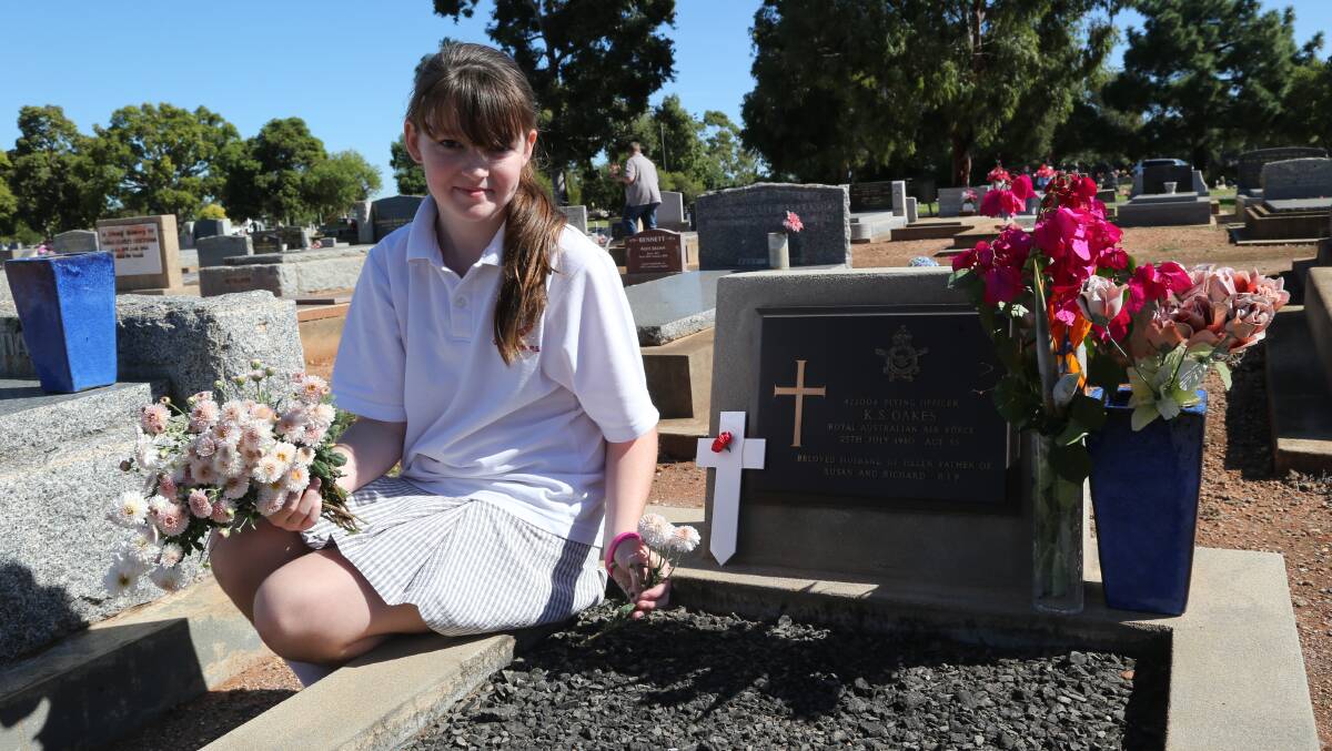 Anzac Day in Griffith. Jenna Oakes, 11, placing a flower on her grandfather's grave. Picture: Anthony Stipo