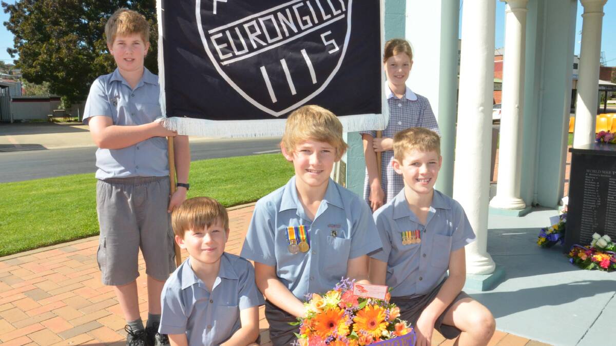 Anzac Day in Junee. Eurongilly Public School students Angus Herbert, 12, and Claire Herbert, 9, holding the sign with Henry Matear, 10, Jarrod MacLeod, 12, and Rhauri MacLeod, 10. Picture: Declan Rurenga 