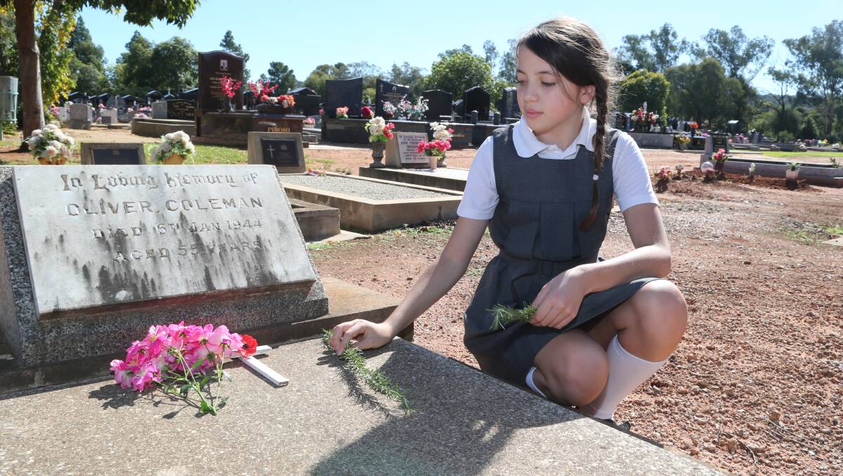 Anzac Day in Griffith. Isabel Salvestro, 11, placing a flower on a soldier's grave. Picture: Anthony Stipo 
