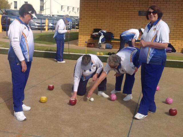 Jeanie Leighton and Jan Carroll watch as Gill Beer and Joan Bourke measure for the winning shot.