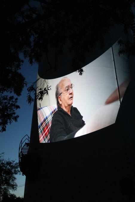 ON SCREEN: Wiradjuri Elder Clarry Higgins shares his stories of Wattle Hill, projected onto the water towers there. Photo: Camille Whitehead