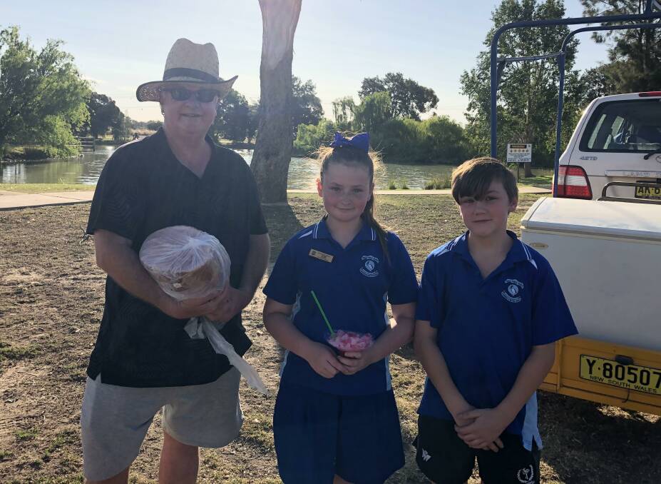 WINNER: Robert Austin accepts a winning ham from Yanco Public School's Alaree Tabain and Leelan Sainsbury-Eyles. Photos: Contributed 