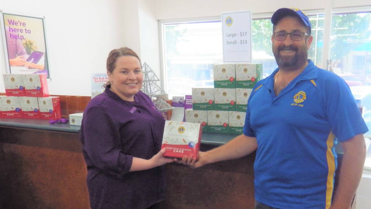 GRAB THEM QUICK: Eliza Smith (left) from Leeton's Beyond Bank branch with Lions Club of Leeton president Frank Pirrottina. Beyond Bank is one location in town where the Christmas cakes can be purchased. Photo: Contributed 