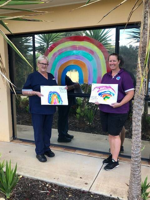 FAMILY LINKS: Carramar's Marian Aliendi and Goodstart Early Learning Centre's Megan Aliendi with the rainbows painted by the children to gift to residents at Carramar. Photo: Contributed 