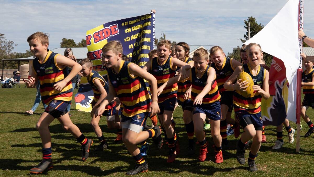 Breaking through the banner in the under 11s grand final. Photo: Andrew McLean Photography
