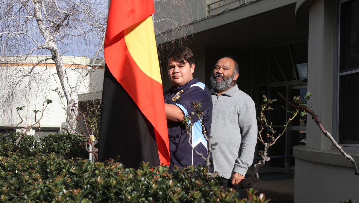 IMPORTANT WEEK: Braith (front) and William Ingram raise the Aboriginal flag outside Leeton Shire Council to kick off NAIDOC Week celebrations. Photo: Talia Pattison