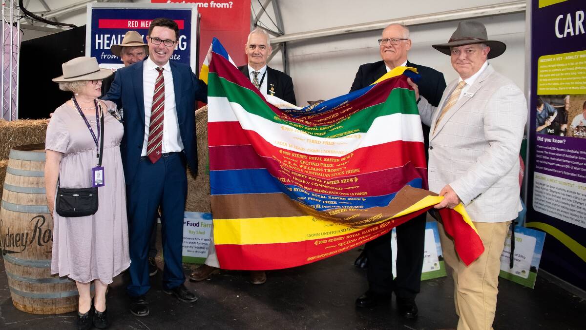 FUNDS: One of the ribbon rugs that was sold as shown here by Minister for Agriculture David Littleproud (second from left), Murray Wilton (far right) and Royal Agricultural Society councillors Sally Evans, Robert Kell, Chris Carter and Geoff Bell. Photo: Supplied 