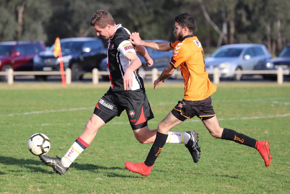 FIELD ACTION: Leeton United's Dan McKenzie gets boot to ball ahead of Wagga United's Nazar Yousif on Sunday afternoon. Photo: Les Smith 