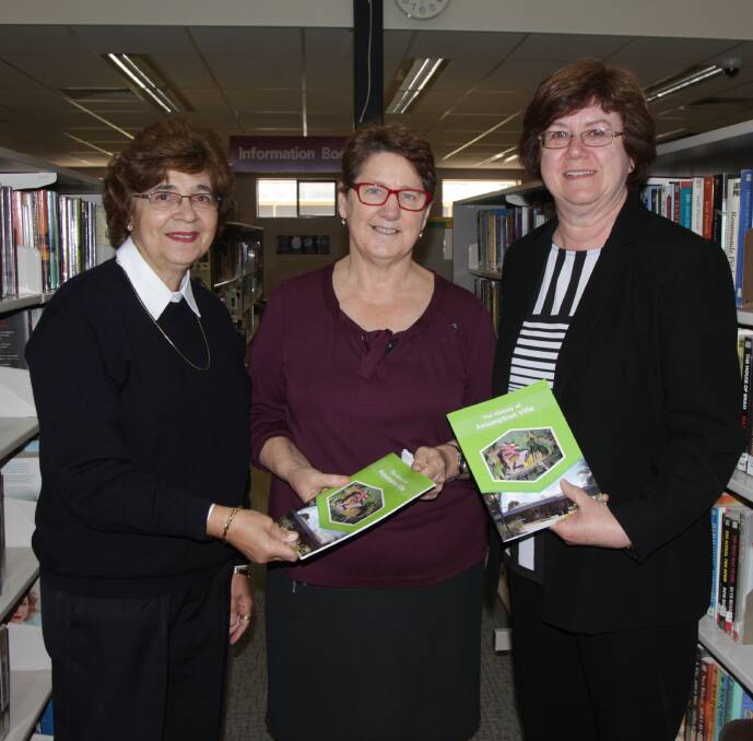 Estella Errey (left) and Carol Chiswell (right) present the book on the history of Assumption Villa to library services manager Lyn Middleton. 