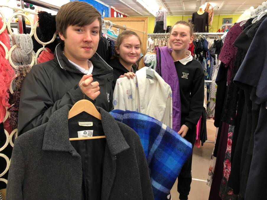 HELPING OUT: Leeton High School students (from left) James Webb, Joannah Currie and Tanahia Woods lend a hand at the Leeton Community Op Shop and show off some of the winters items that are needed. Photo: Talia Pattison