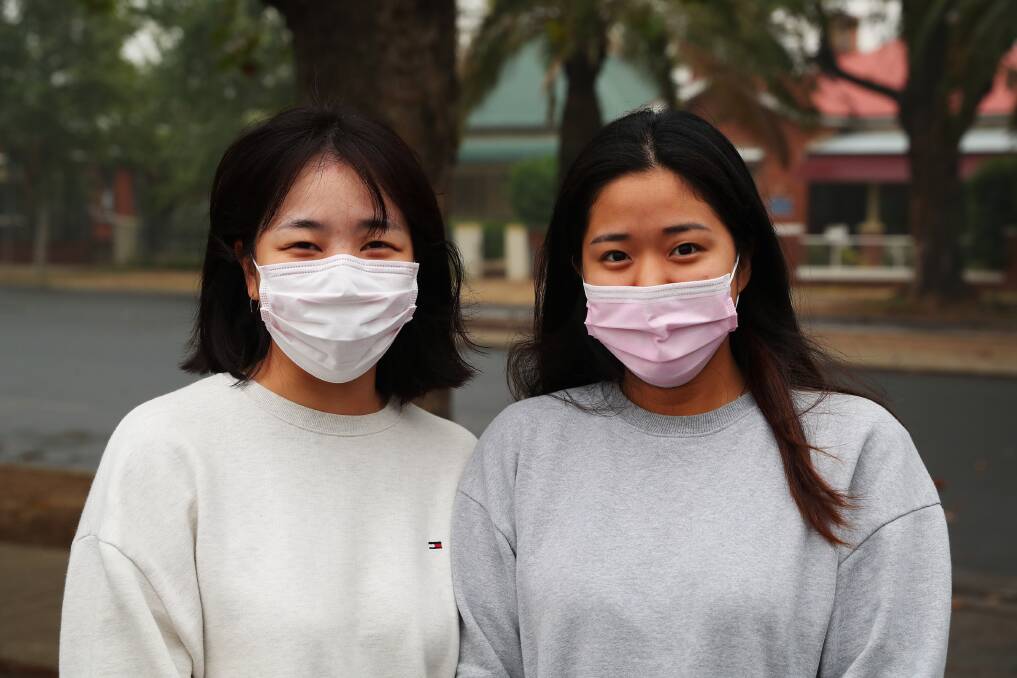 SAFETY FIRST: Korean travelers Mirim Kwon and Yurin Lee try to protect themselves from the hazardous smoke in the Riverina this week. Photo: Emma Hillier