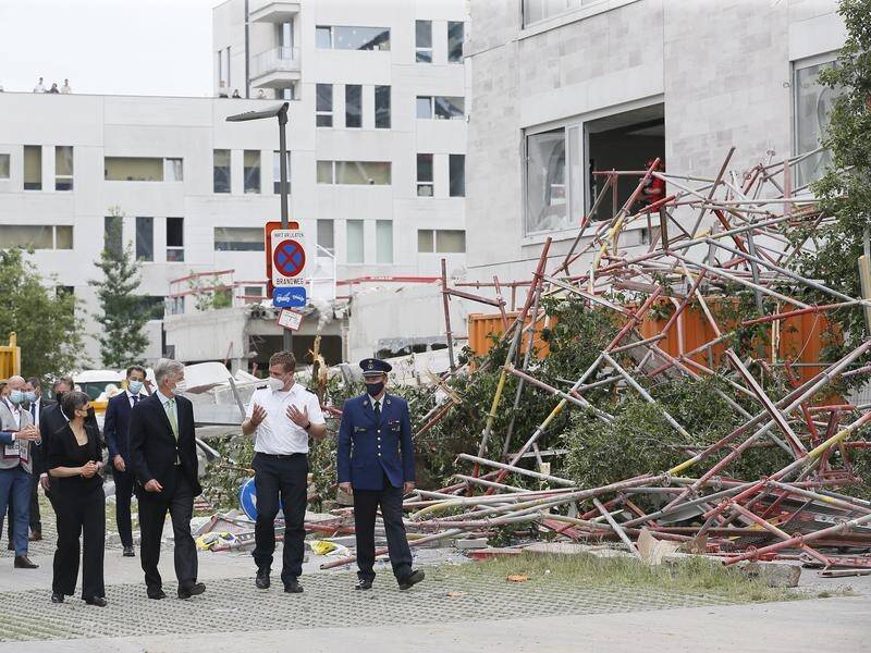 King Philippe of Belgium (C-L) visits paramedics near a building that partially collapsed.